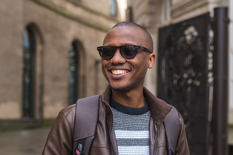 A man wearing sunglasses and smiling in Manchester.