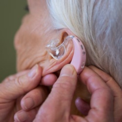 Hearing aid being fitted to an older woman