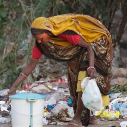 Indian woman bent over, picking up rubbish. Image by Kjell Meek from Pixabay.
