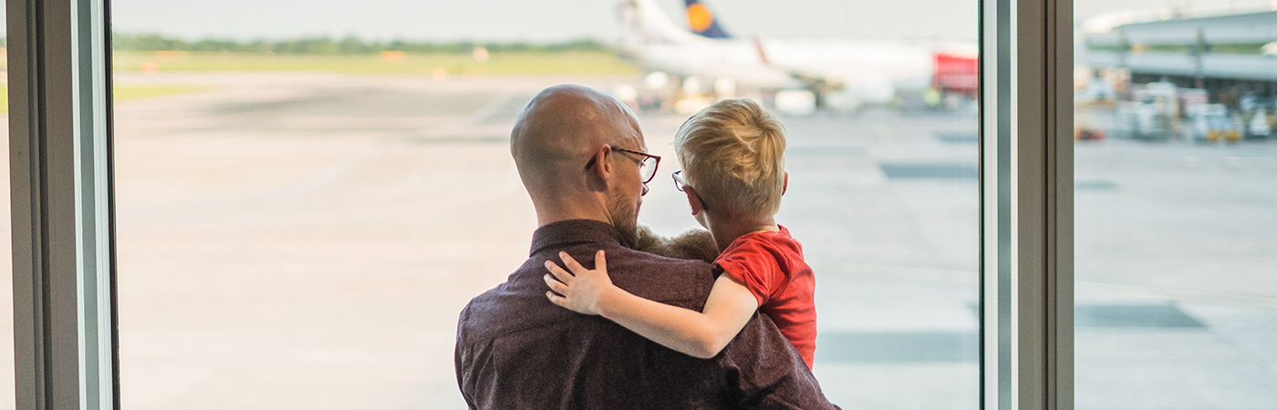 Father and son at an airport watching taxiing aircraft.